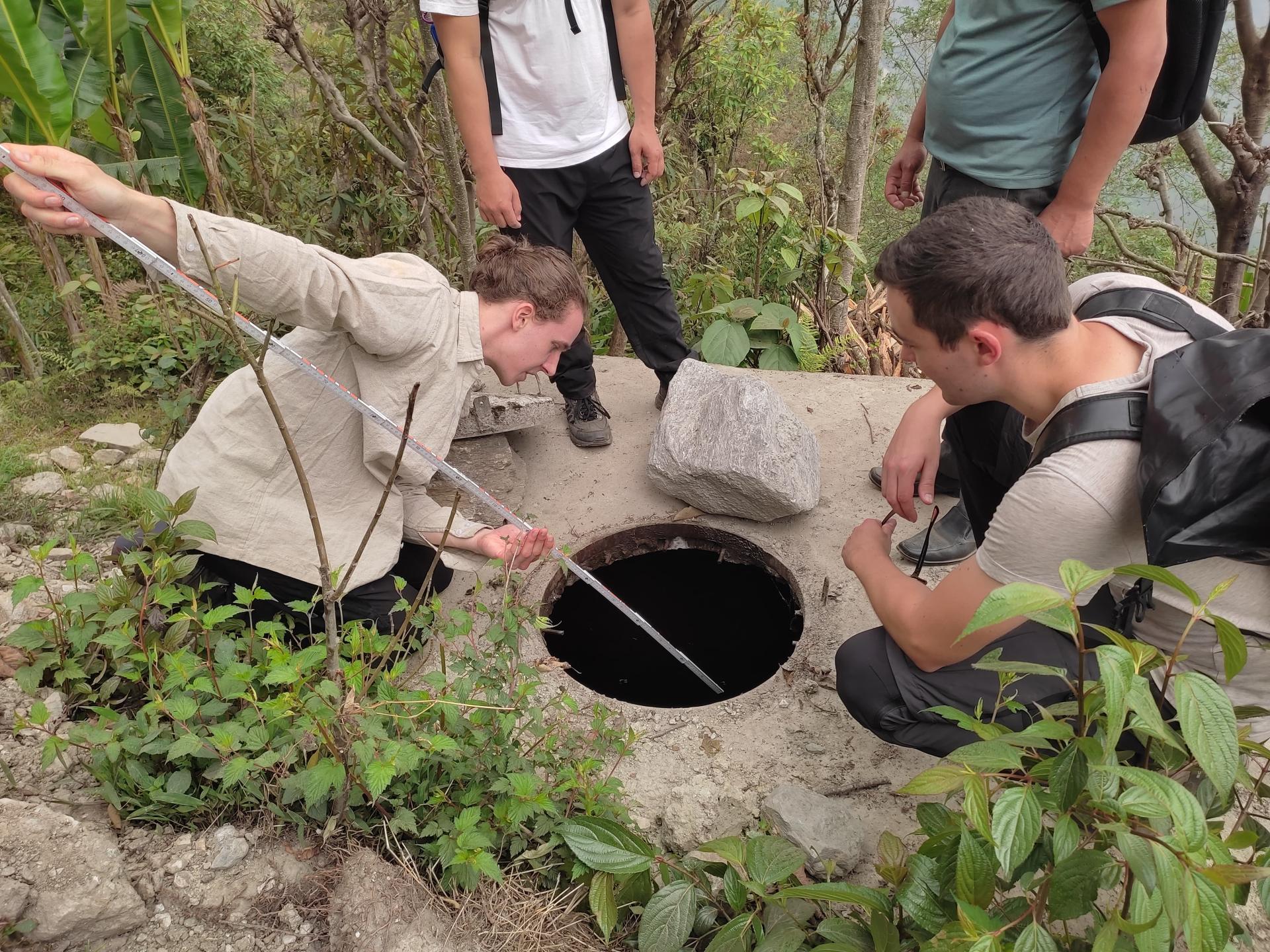 Untersuchung der Wasserquellen - 4 Menschen stehen um ein Loch im Boden