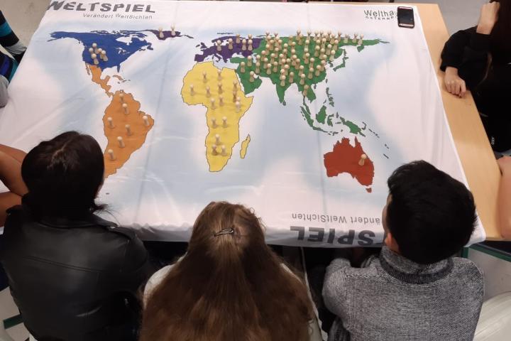 Kinder schauen auf eine Weltkarte