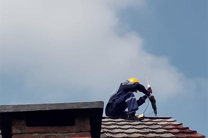 Installateur bringt Blitzableitstab auf Dachspitze ab