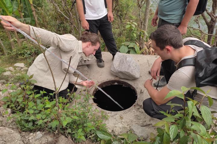 Untersuchung der Wasserquellen - 4 Menschen stehen um ein Loch im Boden