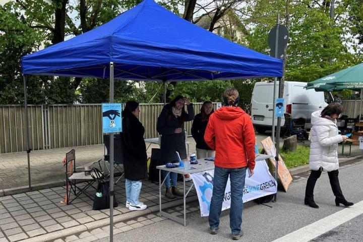 ein Pavillon mit Tisch und Stühlen mit einem dreiköpfigen IOG-Team als Informations-Stand von IOG