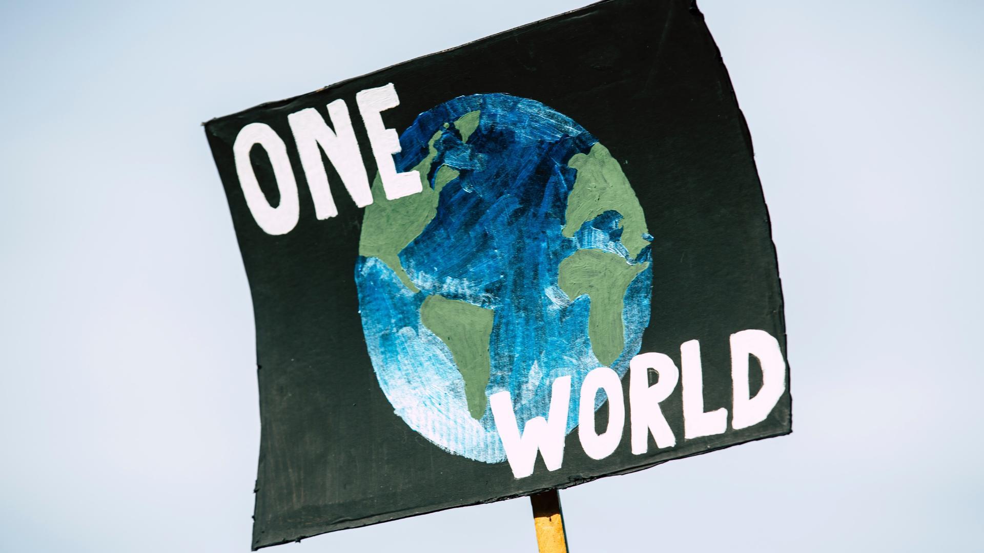 Schild mit Aufschrift "One World"